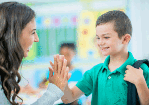 brown-haired women high fiving a kid with a green shirt.
