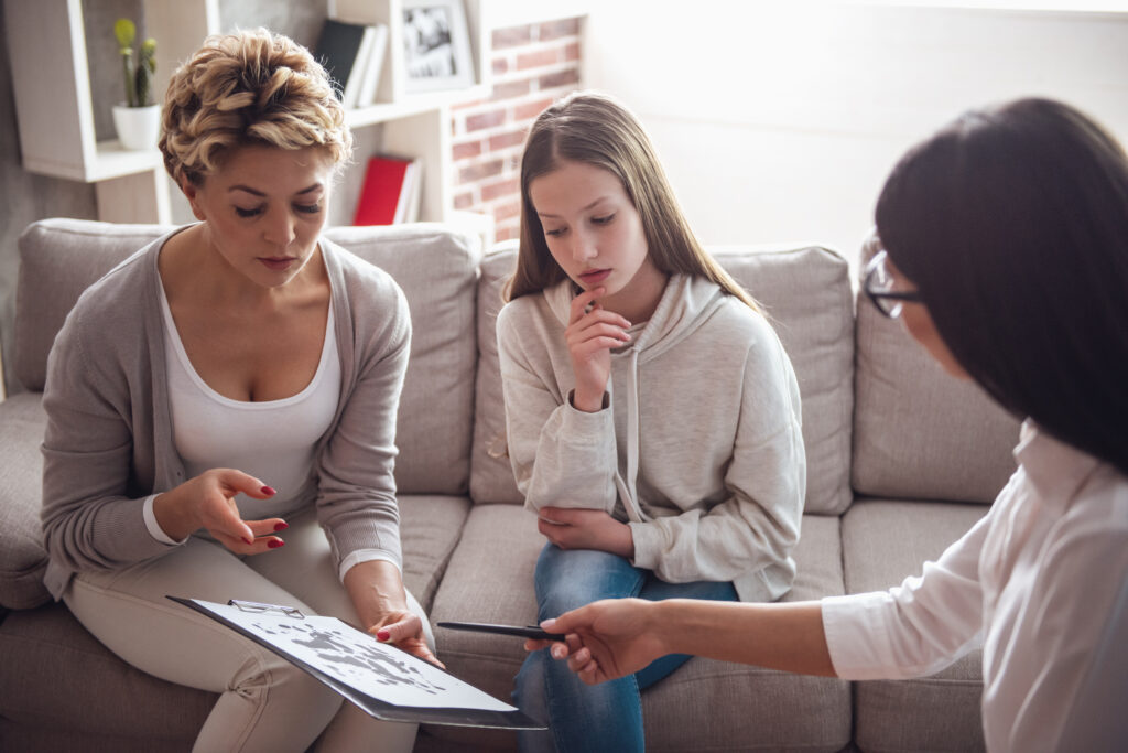 a mom and daughter looking at papers on a chart while talking to someone