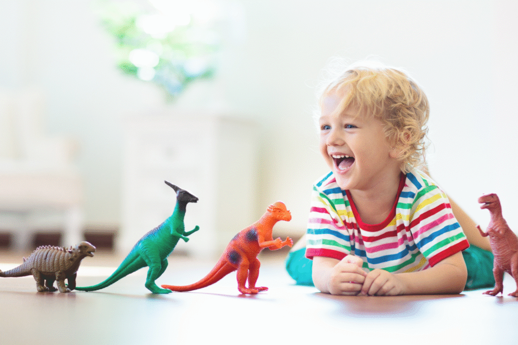 kid whit a colorful striped shirt playing with dinosaurs