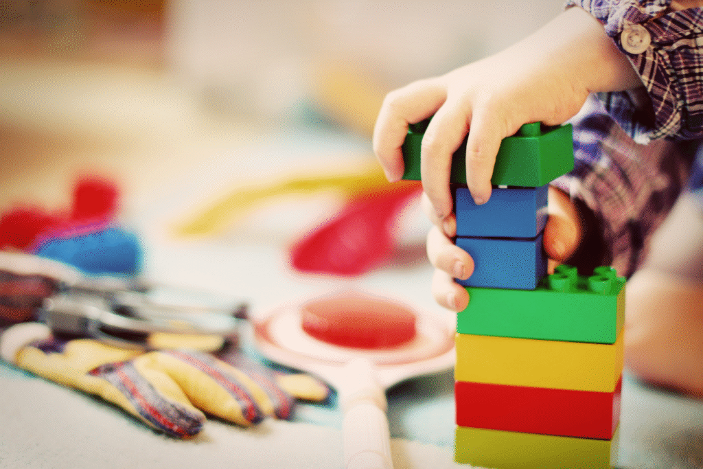 a toddler's hand playing with building blocks