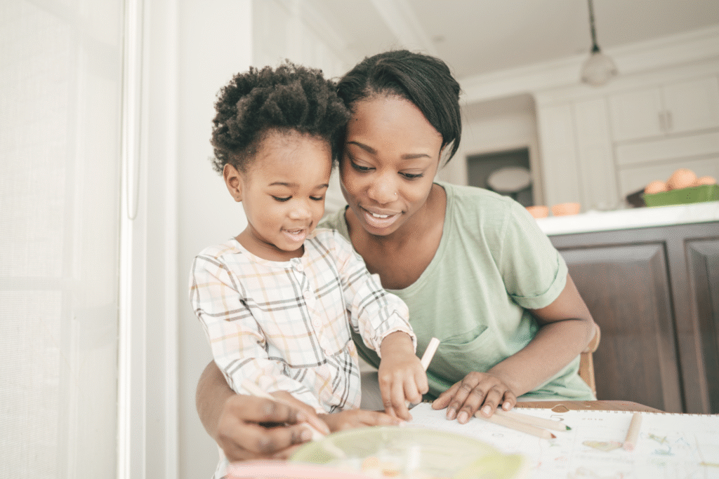 a woman wrapping her arm around a child to help write something for their craft they are doing together