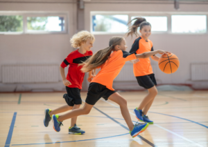 Children playing basketball in gym physical wellness and fitness