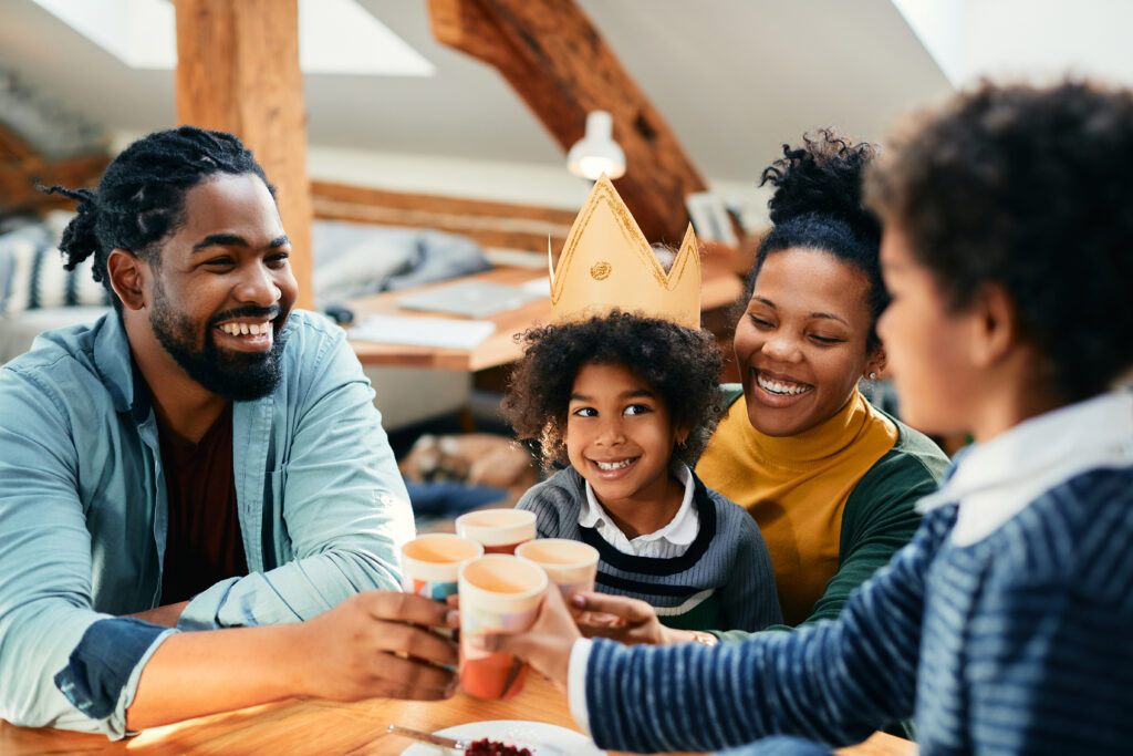 Happy African American girl having fun while toasting with her family during her Birthday party at home.