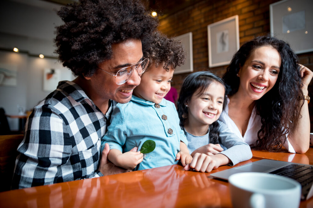 Happy multiethnic family having fun while using laptop together